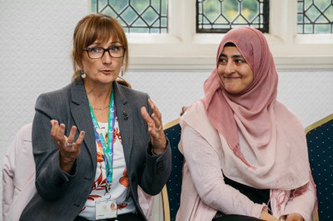 Two women speaking during community meeting