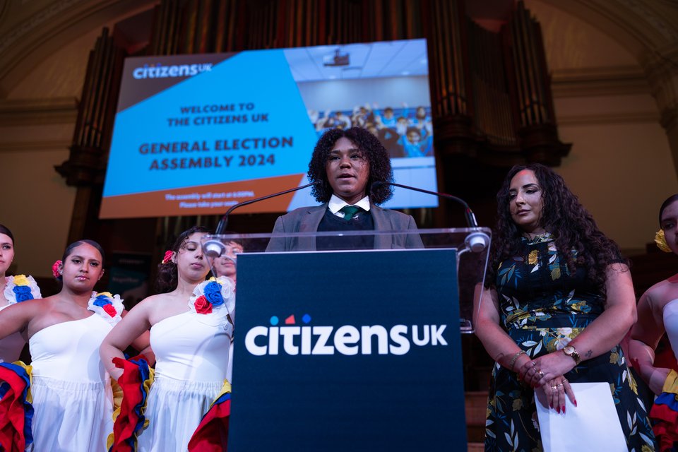 A young leader is introducing the Citizens Assembly with other leaders including dancers.