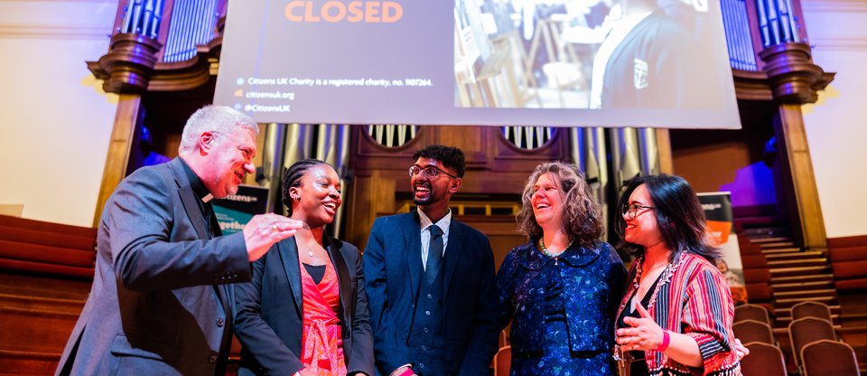 Citizens UK leaders on stage announcing the end of an assembly