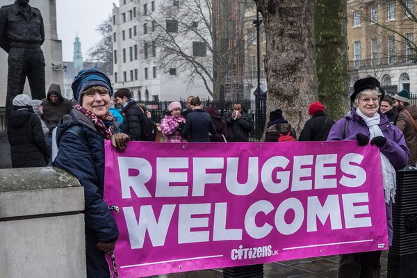 Women holding banner at Refugees Welcome public action