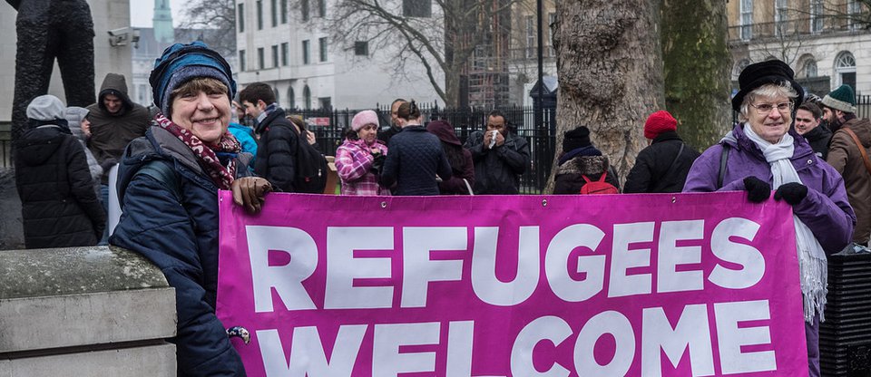 Women holding banner at Refugees Welcome public action