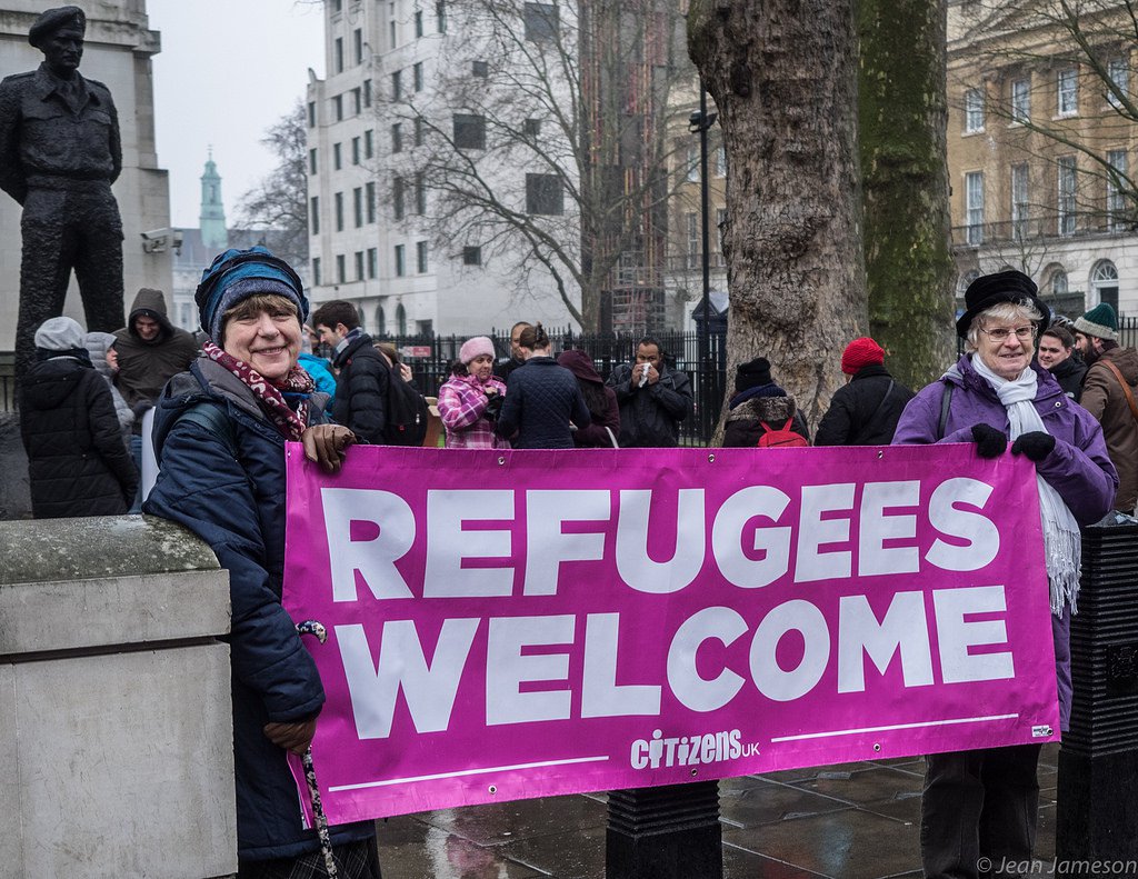 Women holding banner at Refugees Welcome public action