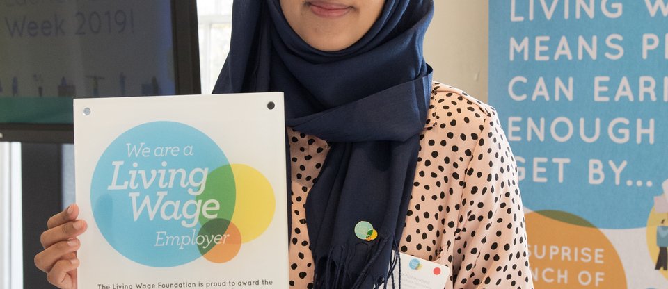 Woman holding up Living Wage poster