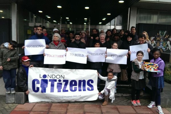 People stand with posters saying  'Working together to build Lewisham Future' and London Citizens Poster for housing action