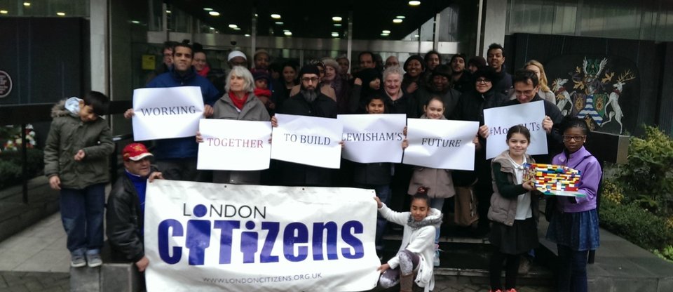 People stand with posters saying  'Working together to build Lewisham Future' and London Citizens Poster for housing action