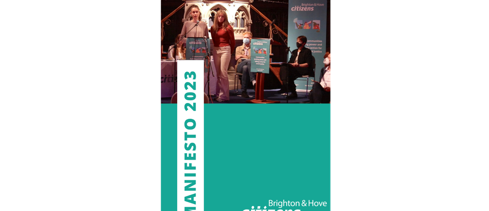 The front cover of the Brighton & Hove Citizens 2023 Manifesto booklet. On the front, two young leaders are on-stage, speaking to an audience