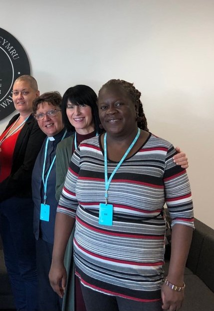 Five community leaders from Citizens Cymru Wales stand smiling with Mark Drakeford, First Minister of Wales.