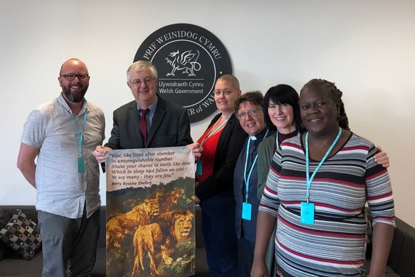 Five community leaders from Citizens Cymru Wales stand smiling with Mark Drakeford, First Minister of Wales.