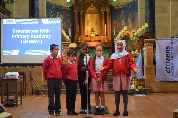 Five young students speak in church hall passionately about refugee welcome school accreditation