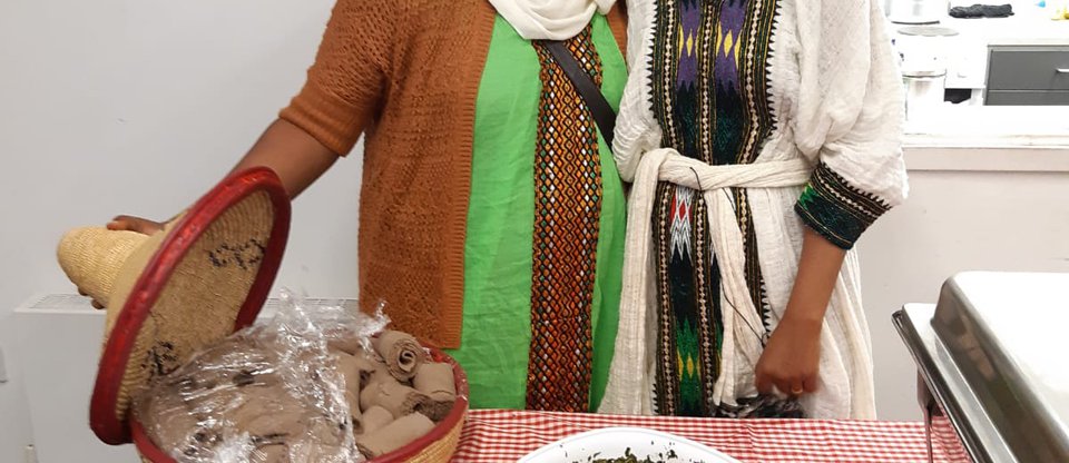 Two volunteers are smiling and revealing food in trays.