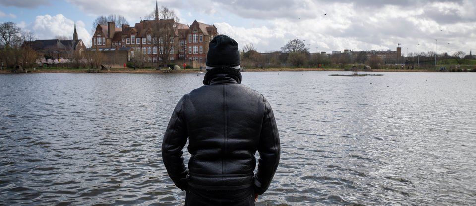 Man standing looking out to a small lake