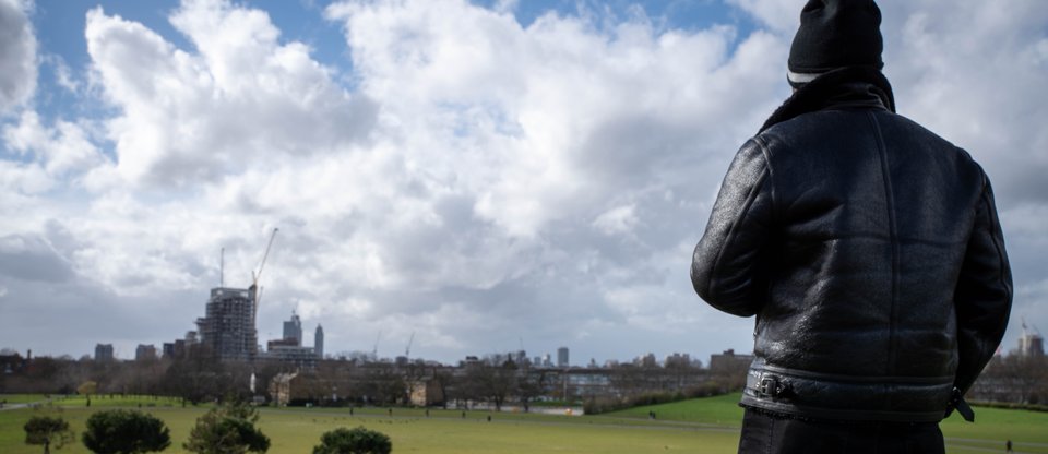 Man in park with his back turned, looking out to city skyline