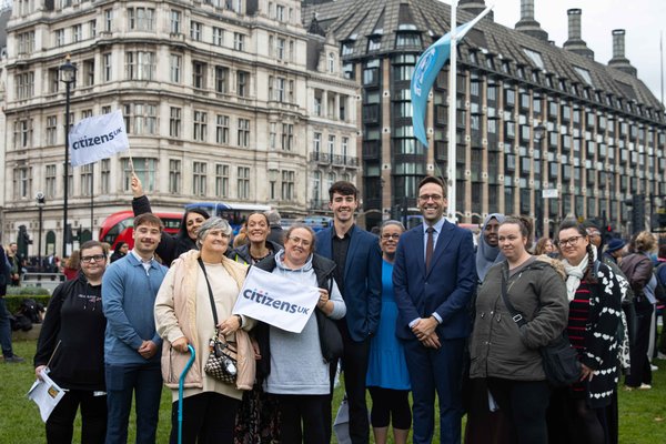 Citizens UK leaders stand in Parliament Square with Citizens UK flags and Big Ben in the background for a housing action