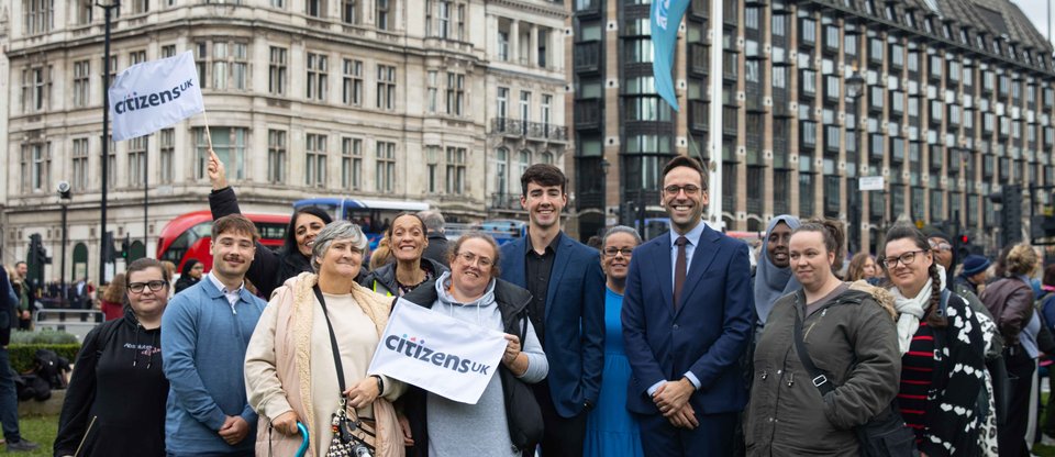 Citizens UK leaders stand in Parliament Square with Citizens UK flags and Big Ben in the background for a housing action