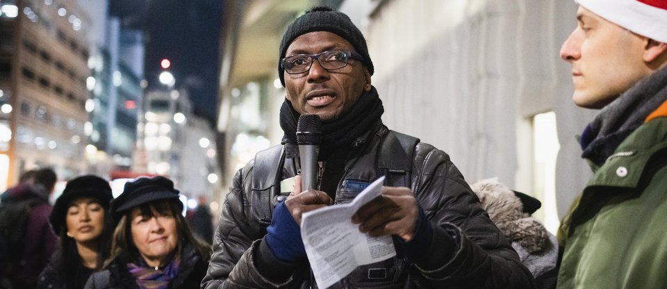 Leader giving testimony with a microphone at a winter Living Wage for Social Care action outside of Barchester Healthcare headquarters in London
