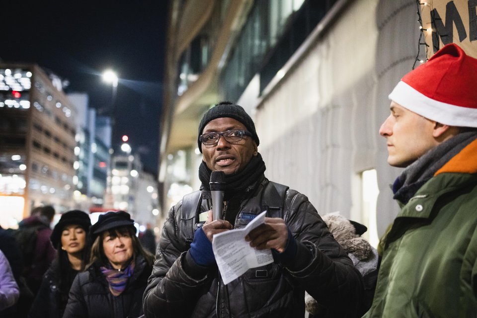 Leader giving testimony with a microphone at a winter Living Wage for Social Care action outside of Barchester Healthcare headquarters in London