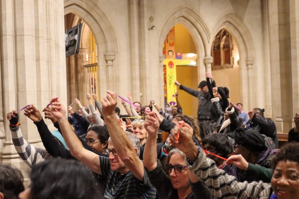 Community leaders are sitting in the Cathedral hall holding up pieces of string at the South London Citizens assembly