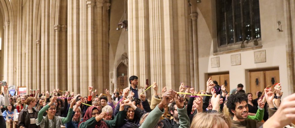 Community leaders are sitting in the Cathedral hall holding up pieces of string at the South London Citizens assembly
