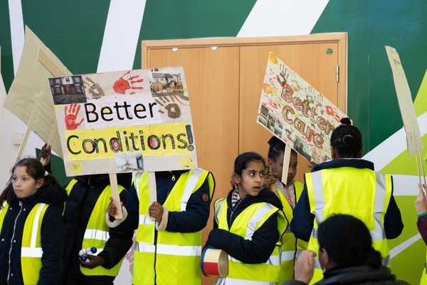 Young campaigners are holding two banners, one reading 'Better conditions', the other 'Better Care'