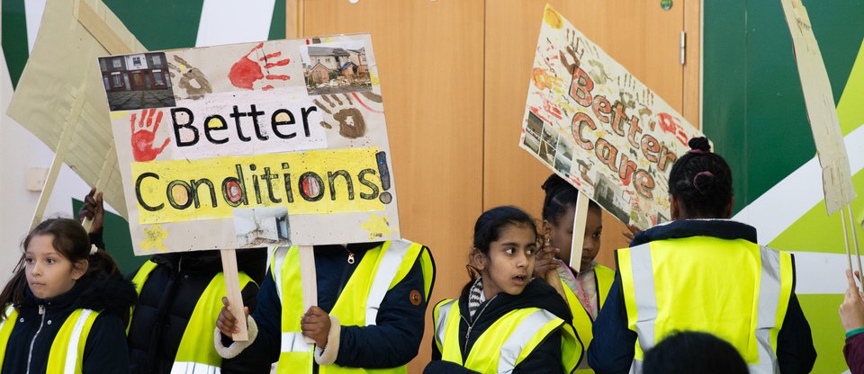 Young campaigners are holding two banners, one reading 'Better conditions', the other 'Better Care'
