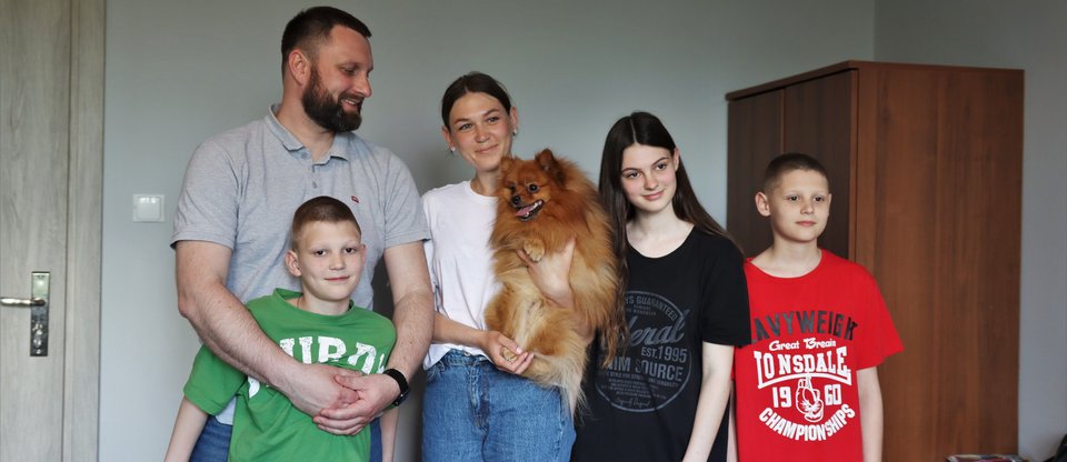 Family of five stand together with mum holding dog