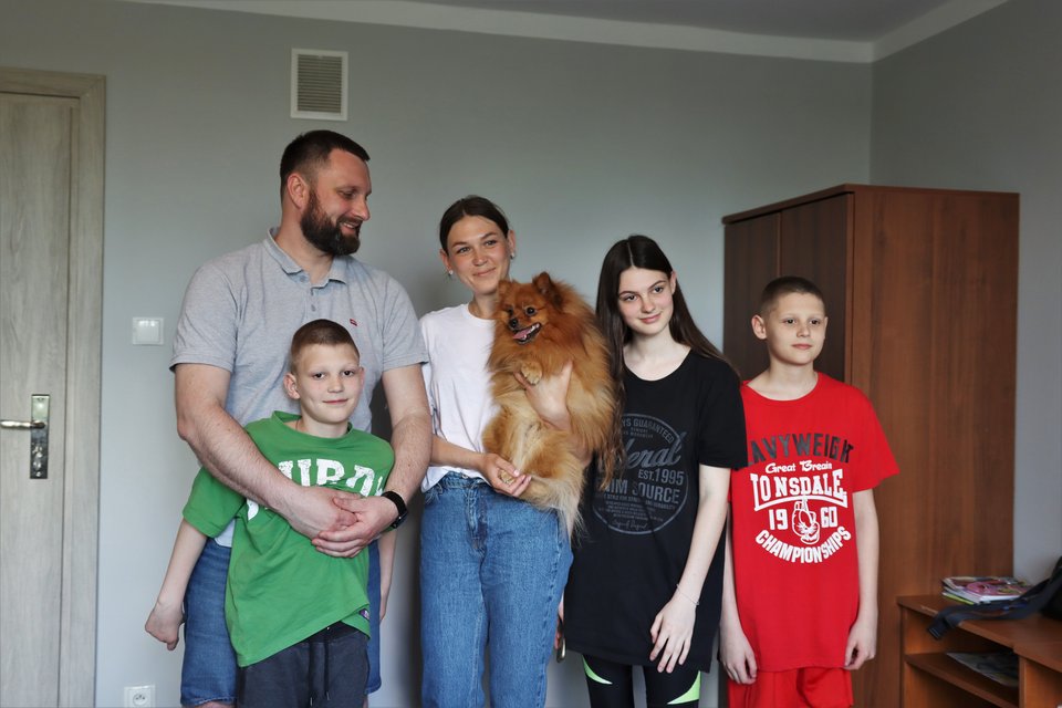 Семья из пяти человек стоит вместе с мамой, держащей собаку