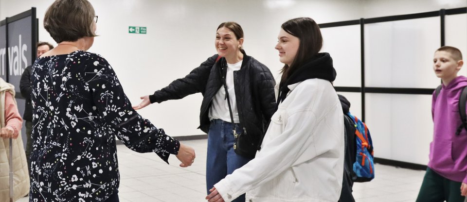 Ukrainian Refugees, mother and children, greet woman at airport arrivals