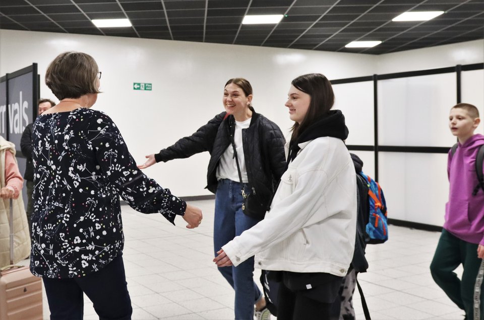 Ukrainian Refugees, mother and children, greet woman at airport arrivals
