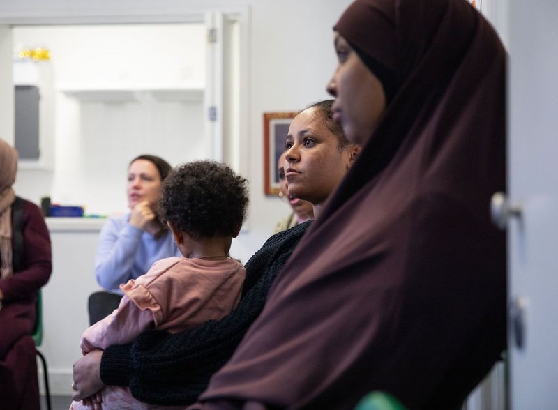 Parents looking ahead, with baby in arms