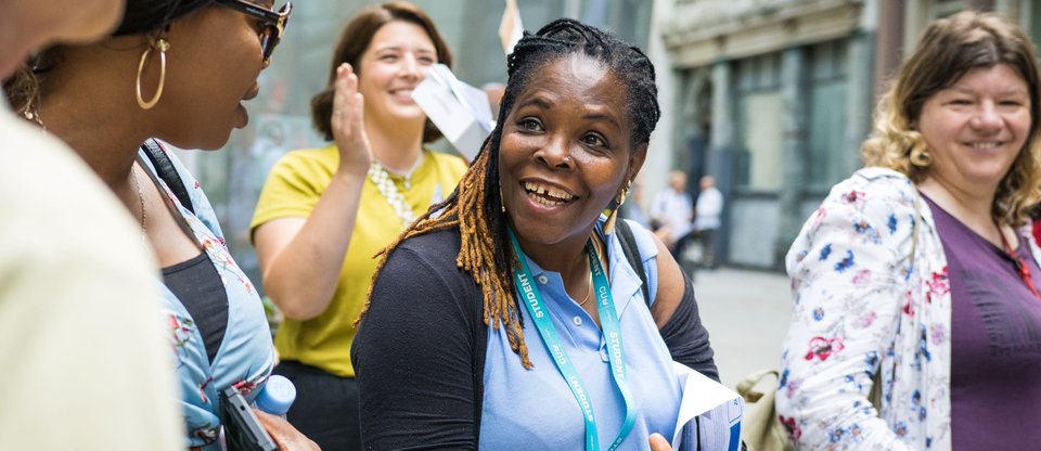 A women is smiling and clapping and surrounded by other people who are also smiling at a protest for the real Living Wage