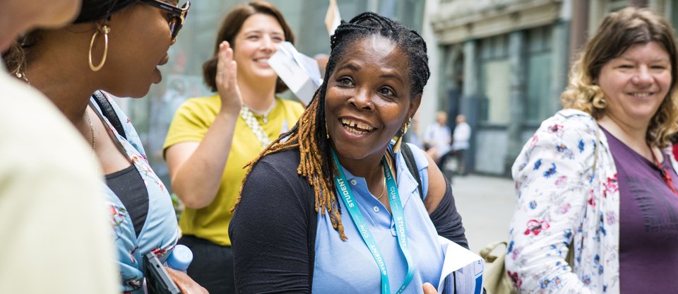 Woman smiling clapping hands with people smiling behind her at an Living Wage for Social Care action
