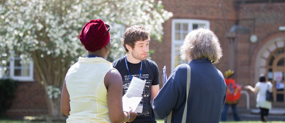 Man speaking to two people outside in a garden