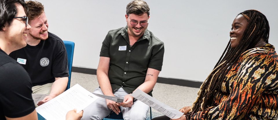 People sitting together talking and laughing while holding paper in training session