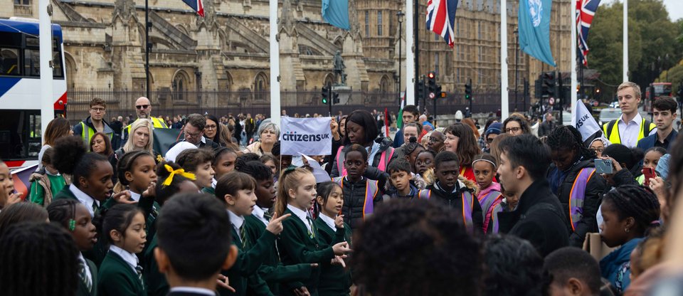 Citizens UK leaders gather at Parliament Square for a housing action, watching St Antony's students perform a song with Parliament behind them