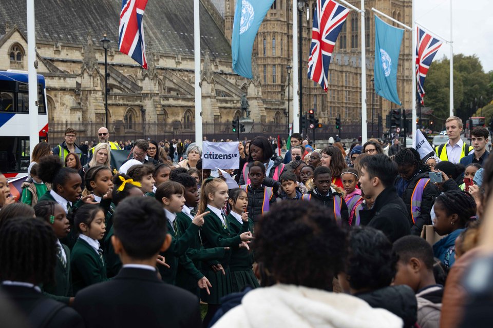 Citizens UK leaders gather at Parliament Square for a housing action, watching St Antony's students perform a song with Parliament behind them