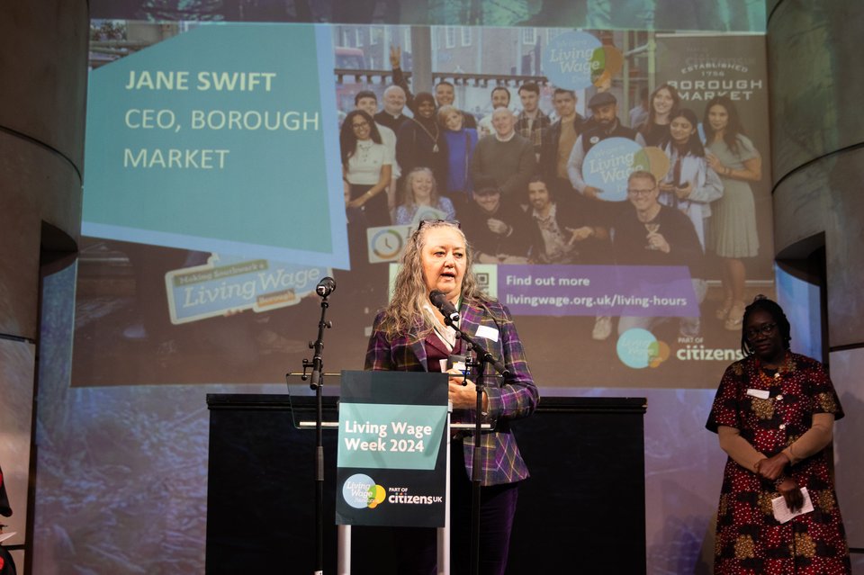 Jane Swift, CEO of Borough Market, stands at a podium centre stage giving a speech