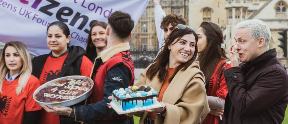Members of East London Citizens alliance holding cakes outside the Houses of Parliament advocating for a real living wage
