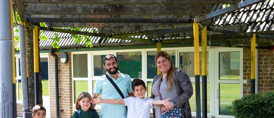 Sponsored Refugee family of five smiling outside school