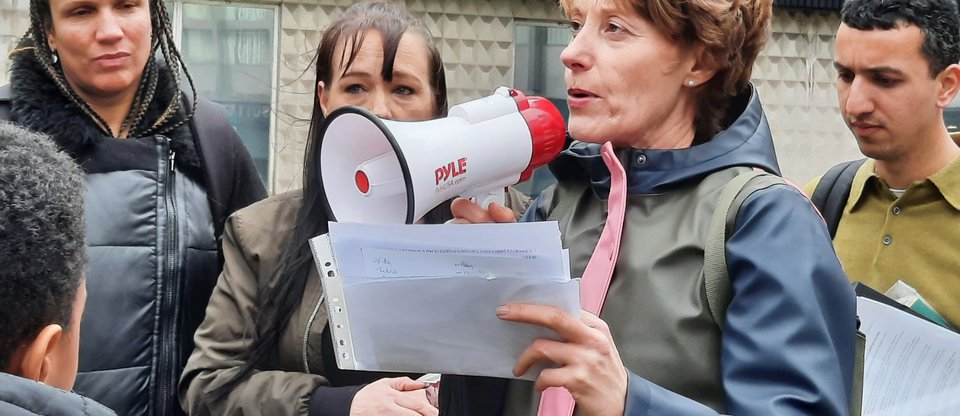 A woman is holding a megaphone and is reading a speech against poor housing.