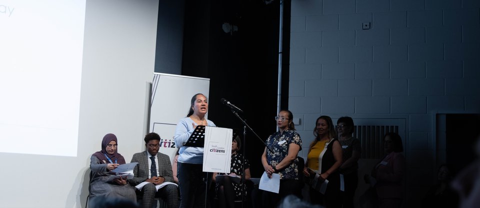 A community leader stands and speaks on stage.