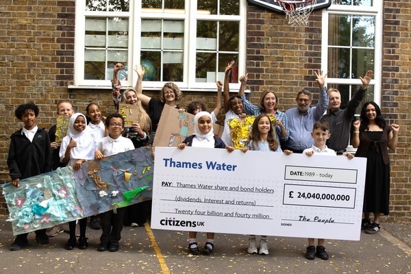 Adults and young people holding a giant cheque for £24 billion and collage artworks