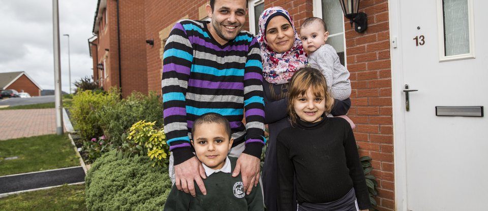 Family with two parents and three children standing outside a house