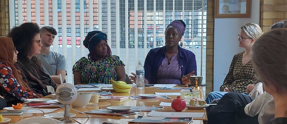 Staff are seated around a table, attending a Race Equity and Cultural Heritage (REACH) Network meeting