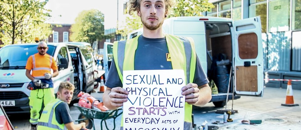 Greater Manchester Citizens action, 2018, Construction worker holds sign reading "sexual and physical violence starts with everyday acts of misogyny"