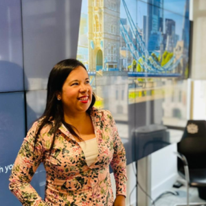 Citizens UK leader Gina Rodriguez stands smiling in a meeting room as she presents