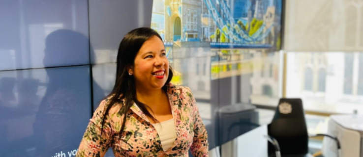 Citizens UK leader Gina Rodriguez stands smiling in a meeting room as she presents