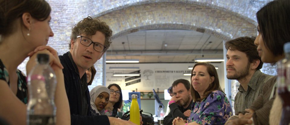 Staff are gathered around a table, taking it in turns to share ideas