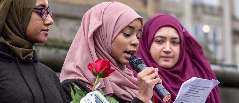 Woman speaking with two women standing next to her holding a rose