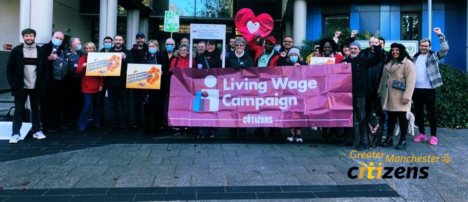 People stand together with Living Wage Campaign signs and posters outside Anchor Hanover care HQ