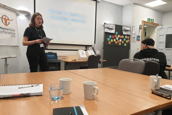 A campaigner speaks in a meeting room about their campaign for inclusive healthcare for trans and non binary people.